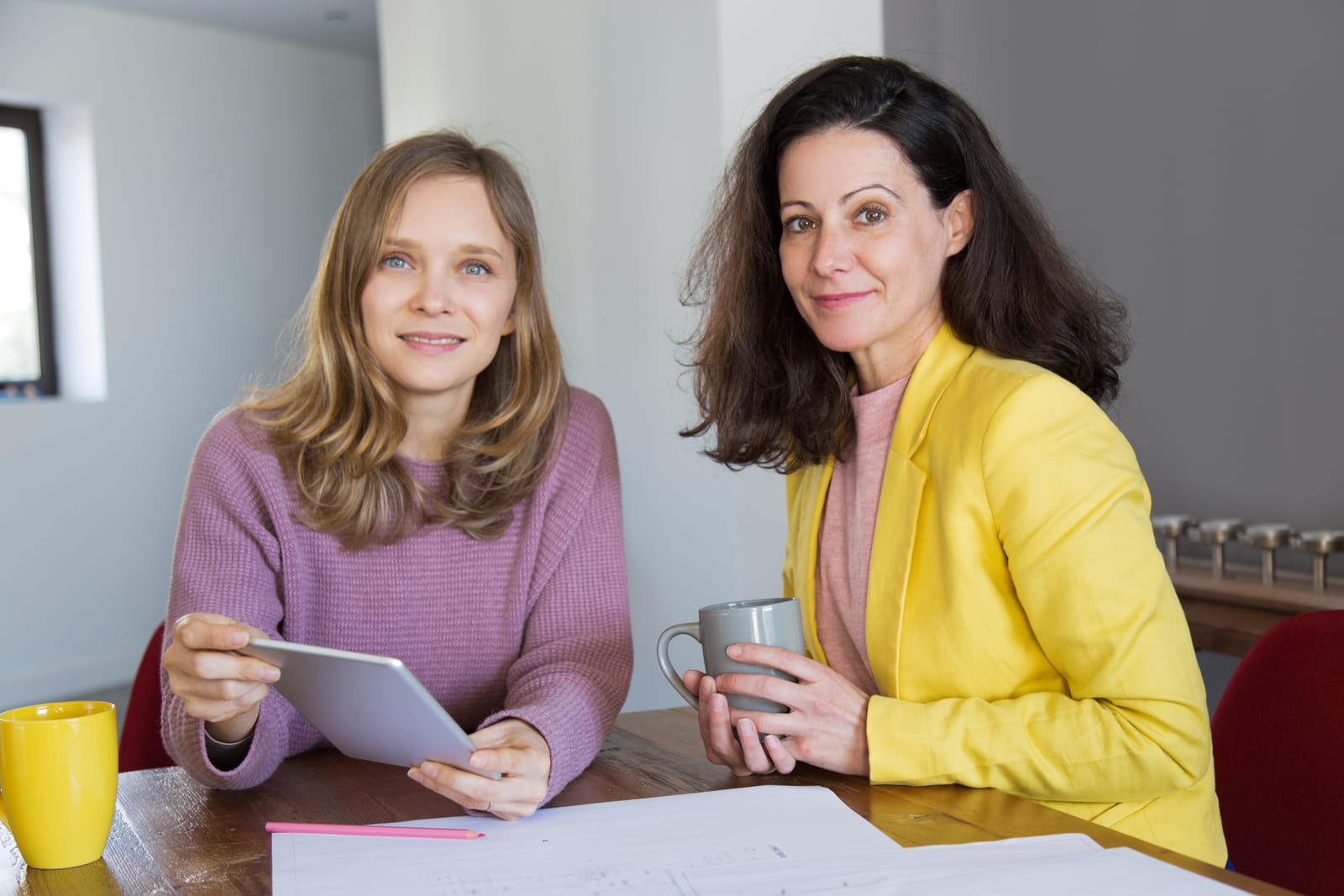 Two colleagues smiling while reviewing a tablet together