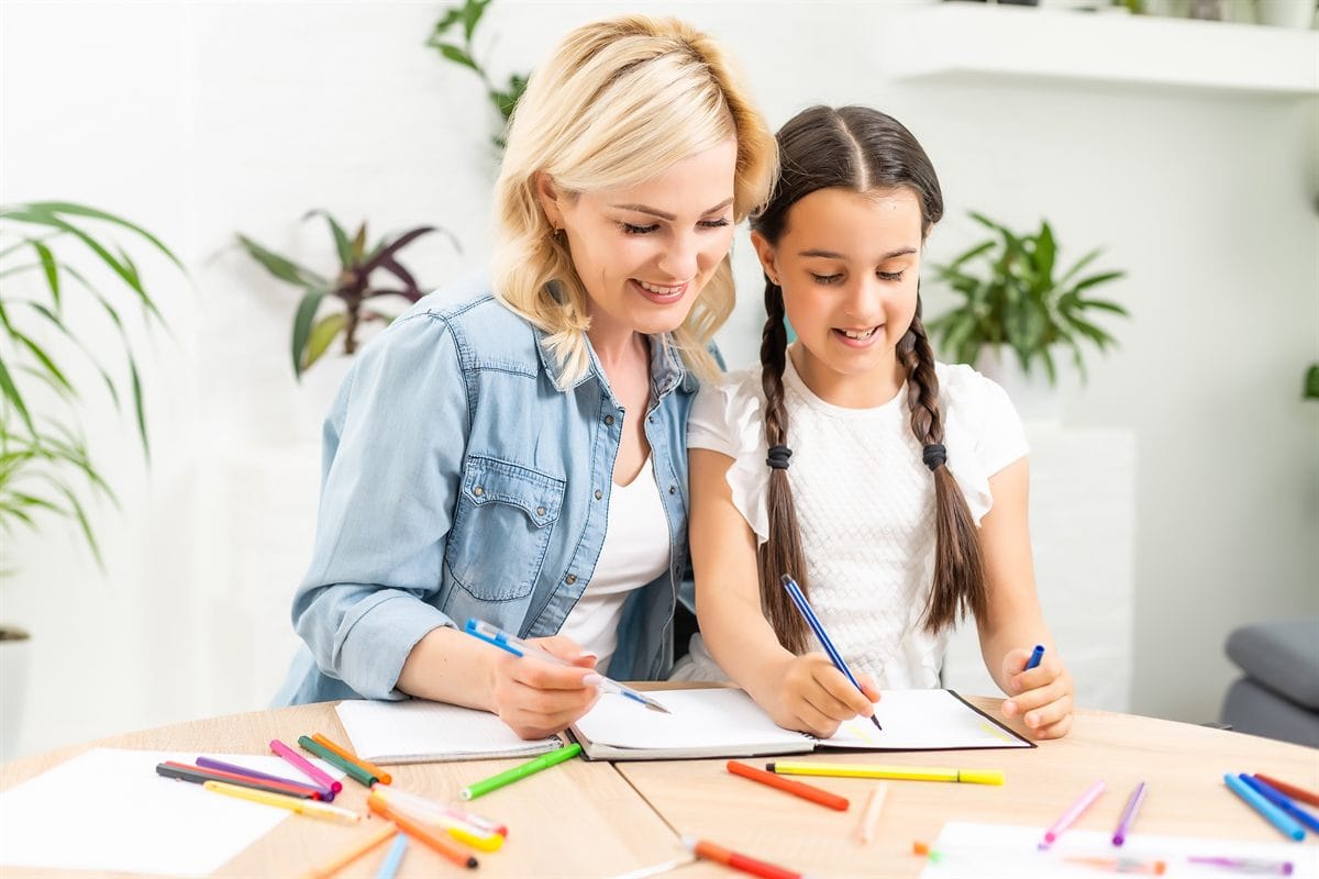 A mother and daughter having fun painting together with colors at home